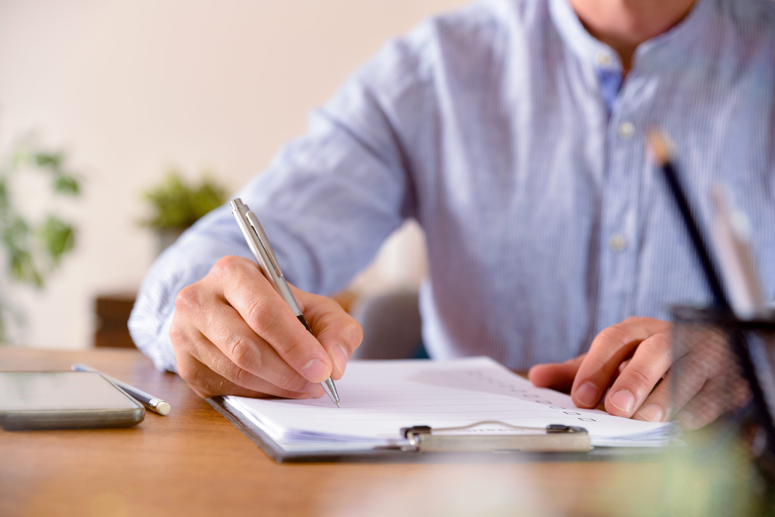 Man filling out a questionnaire on a wooden table front